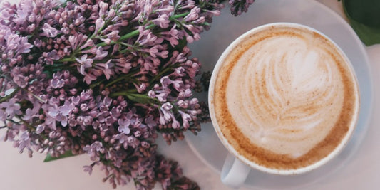 Coffee in a mug, next to some beautiful flowers